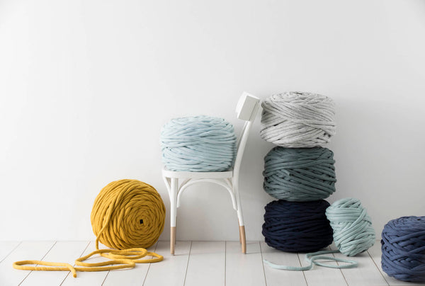 Different colours of K1S1 Extreme Yarn stacked together near a wall. image by Samantha MacAdam Cooper