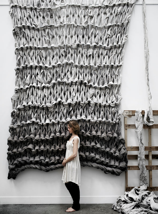 Full length view showing the full scale of Solace I, a hand crafted and arm knitted art installation using felted merino wools in grey hues. Image by Sharyn Cairns