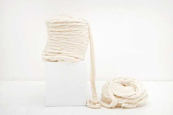 Image of a bump of unspun wool, otherwise known as roving or woollen top resting on a plinth.