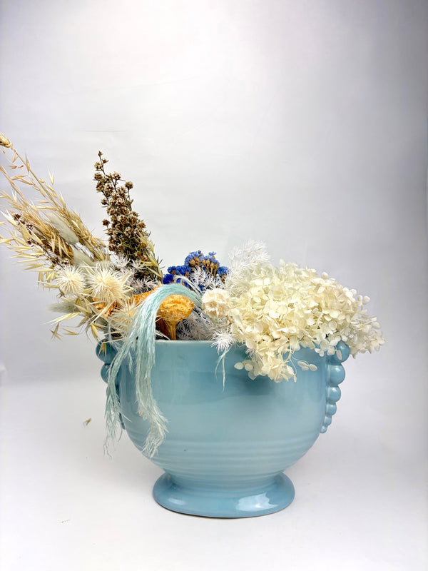 Light blue ceramic vase with dried flowers on a white background