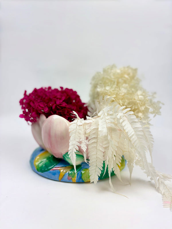 Decorative arrangement with pink and white flowers on a vintage hand-painted Clarice Cliff lotus bowl vase against a white background