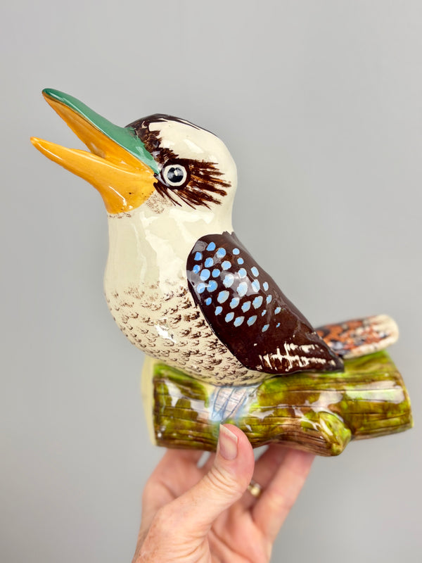 L. Montague kookaburra held in hand against a grey wall for scale, showing the fine brushwork on the head and beak
