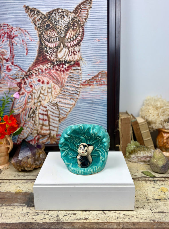 Vintage MCP Disney Flower Skunk wall pocket displayed on plinth with vintage tabletop styling