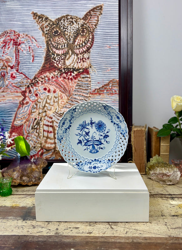 Vintage Meissen Blue Onion reticulated bowl displayed upright on a stand atop a white plinth, with owl artwork, books and crystals behind